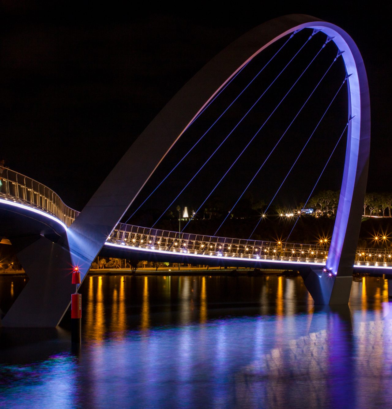 Illuminated Elizabeth Quay bridge arch and golden waterfront reflections.
