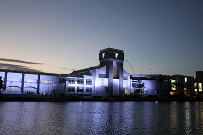 White-lit Myer facade at Pacific Fair reflected in the river at dusk.