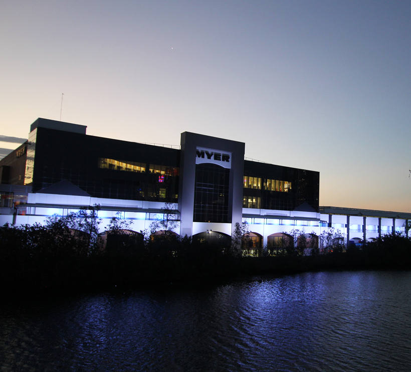 Retail building at Pacific Fair with white facade lighting beside the river.