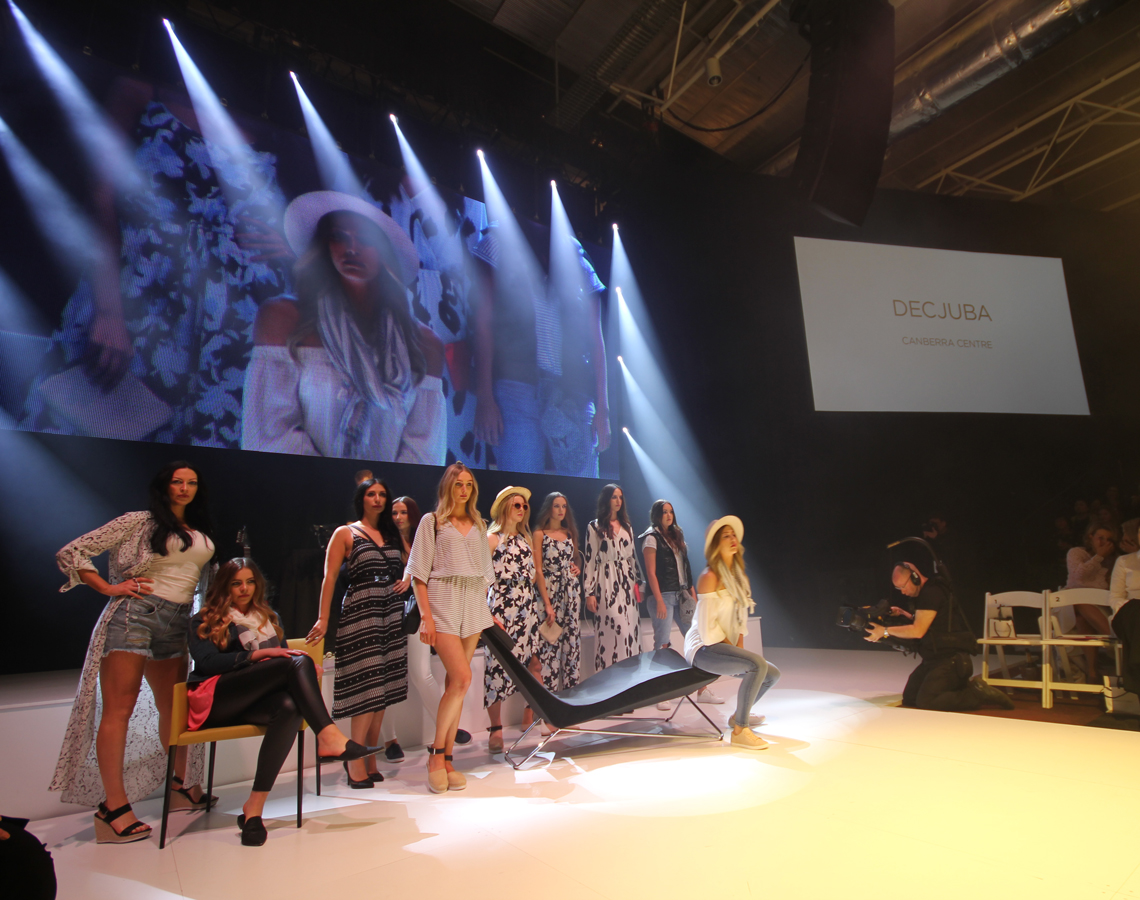 Models lined up onstage beneath white spotlights at FashFest 2016.