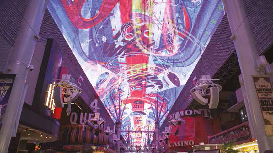 Colourful overhead digital imagery above a busy indoor public space.