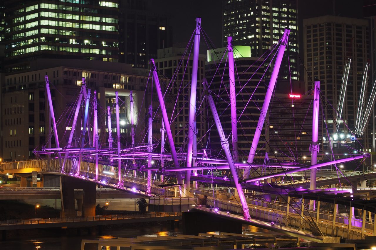 Purple architectural lighting on Kurilpa Bridge's angled masts.