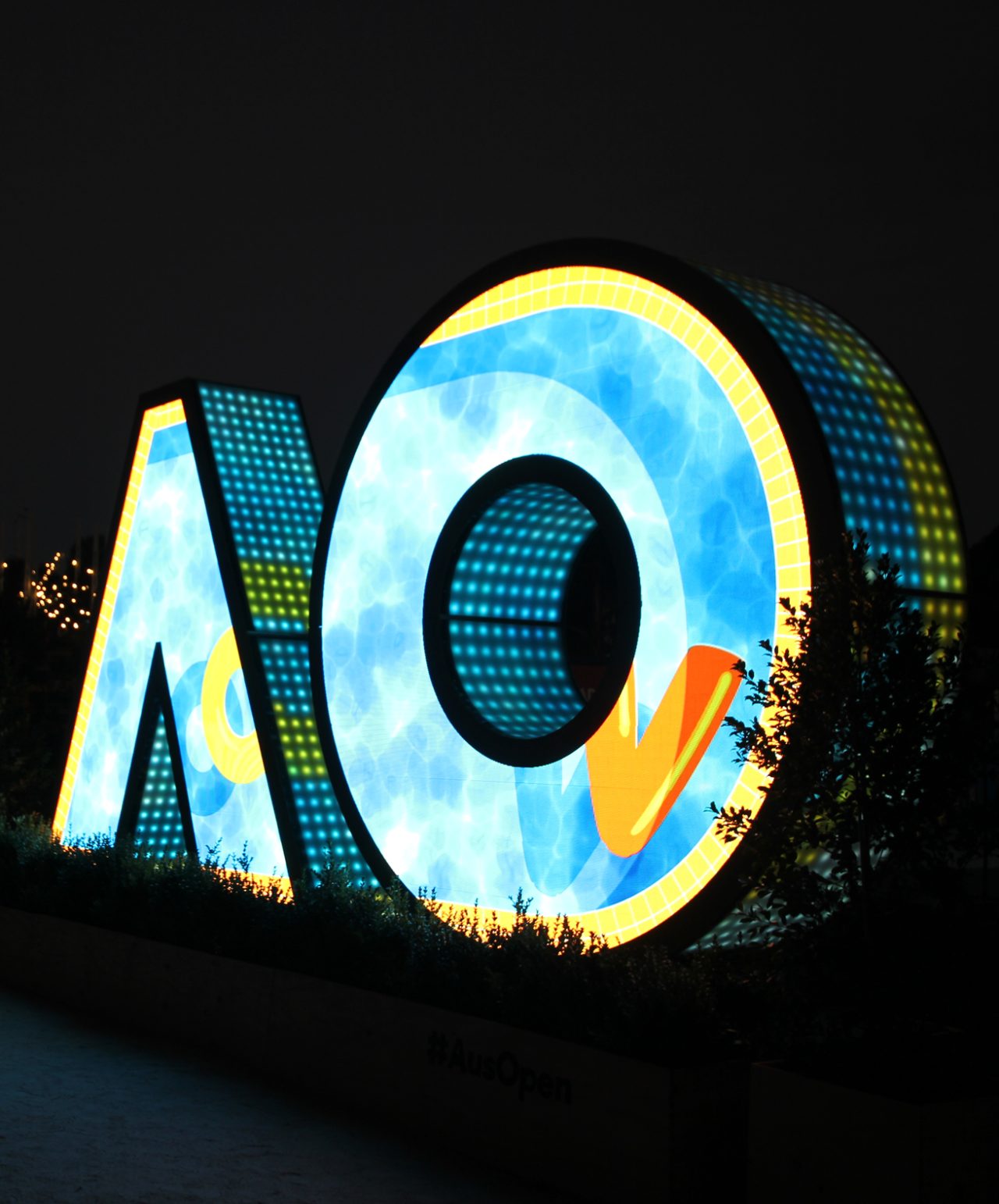 Blue and yellow imagery across the AO digital sign at night.