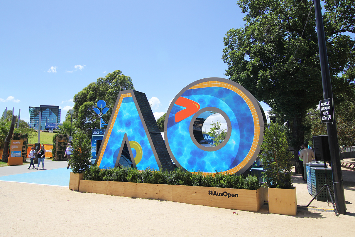 Colourful video imagery fills the AO-shaped digital sign at the Australian Open in daylight.