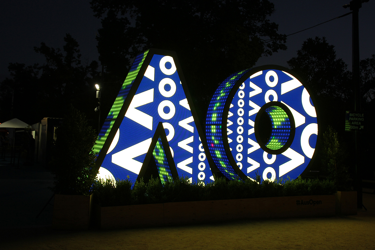 Blue, white and yellow patterns across the AO digital sign at night.
