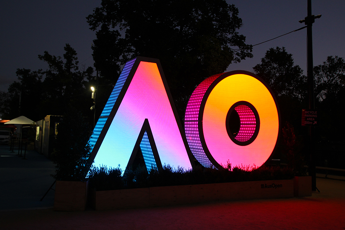 Pink, yellow and blue gradients across the AO digital sign at night.