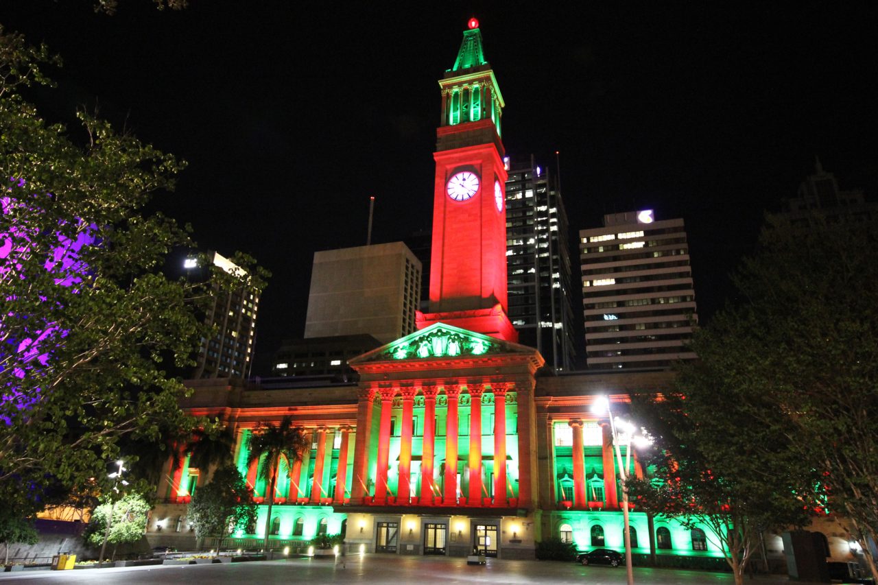 Red and green lighting on Brisbane City Hall and its clock tower at night.