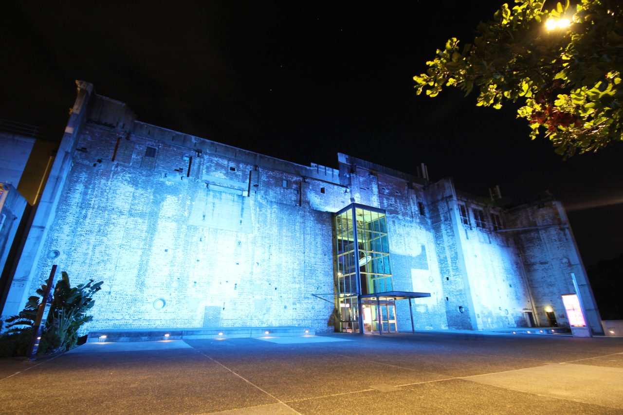 Brisbane Powerhouse exterior illuminated blue at night.