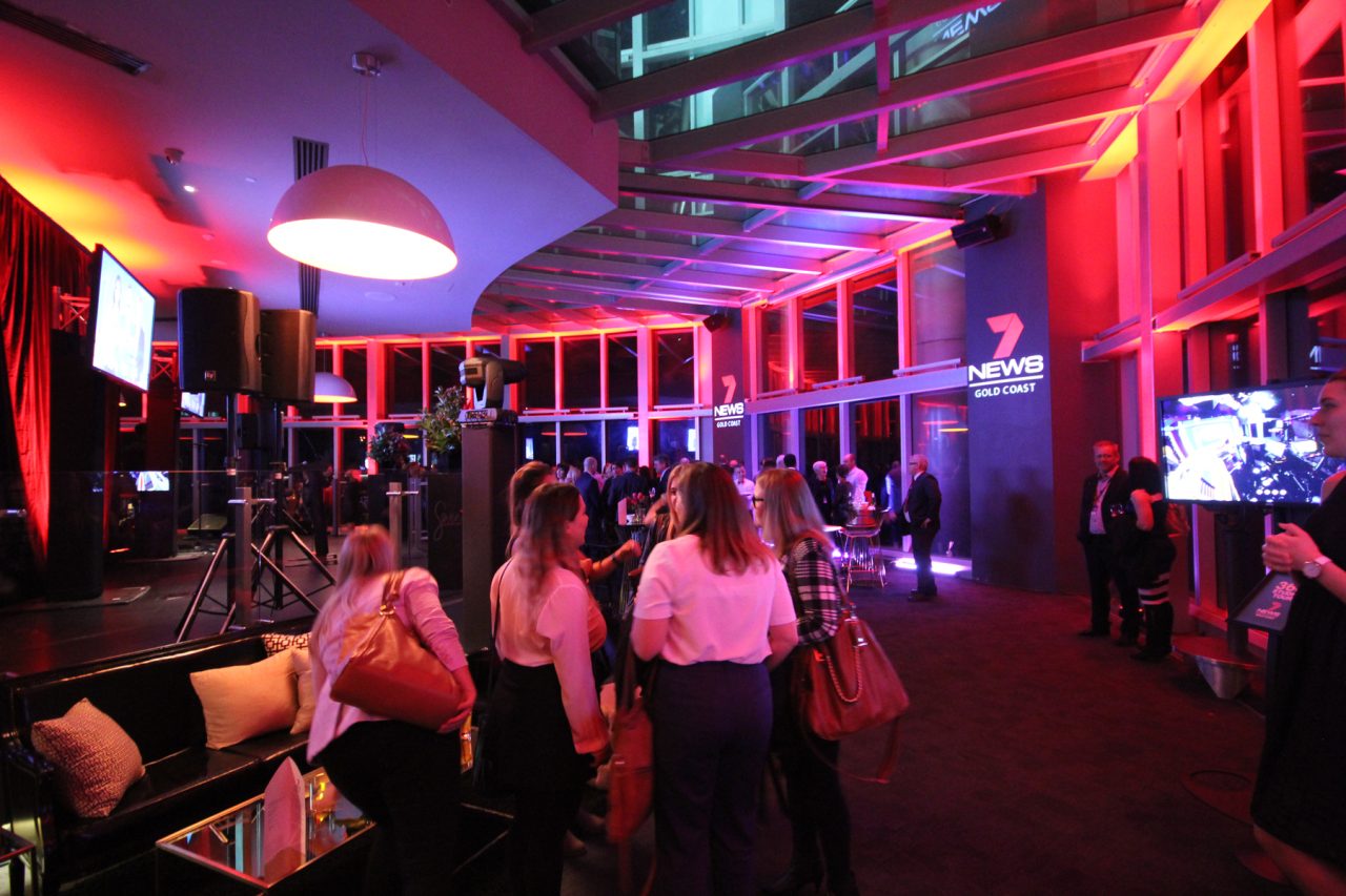 Guests at the Channel 7 News Gold Coast launch beneath red and purple event lighting.