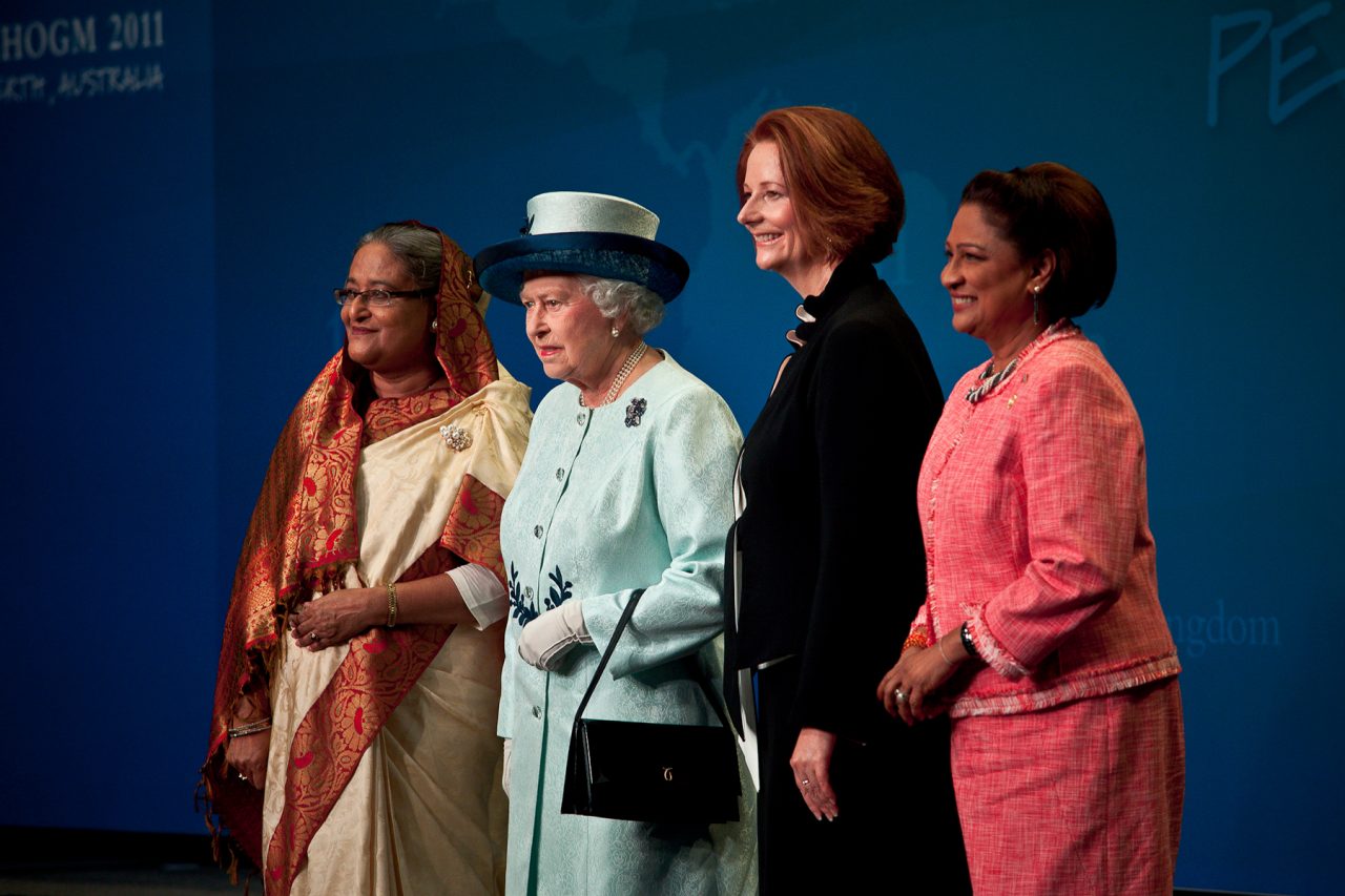 Four attendees pose together against a blue CHOGM 2011 backdrop.