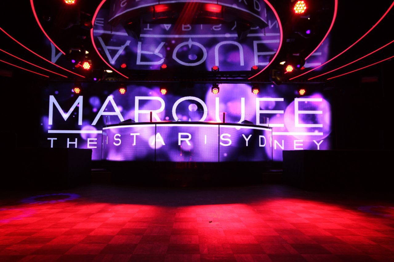 Red lighting across the floor beneath the Marquee video screen at The Star Sydney.