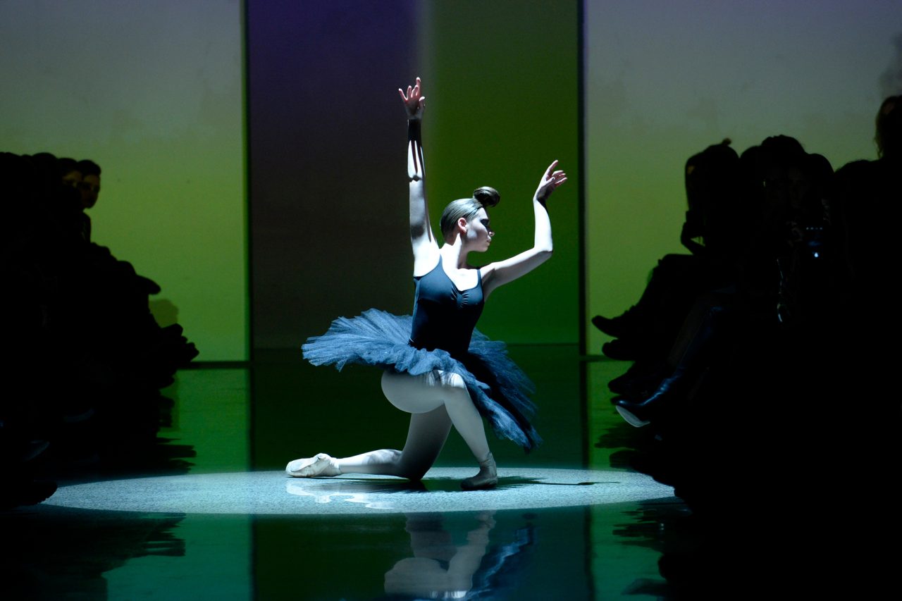 A dancer performs in a spotlight on the runway at New Zealand Fashion Week.
