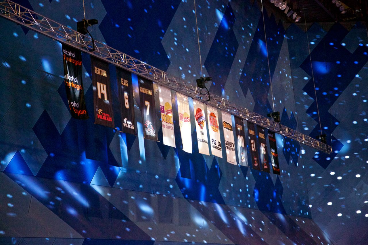 Blue lighting and projected patterns around the banners in the Perth Wildcats arena.