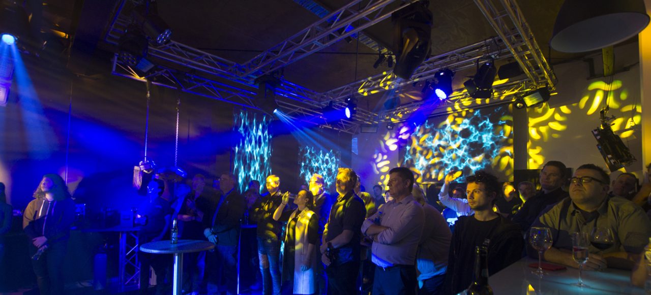 Showroom guests surrounded by blue beams and yellow patterned projections.