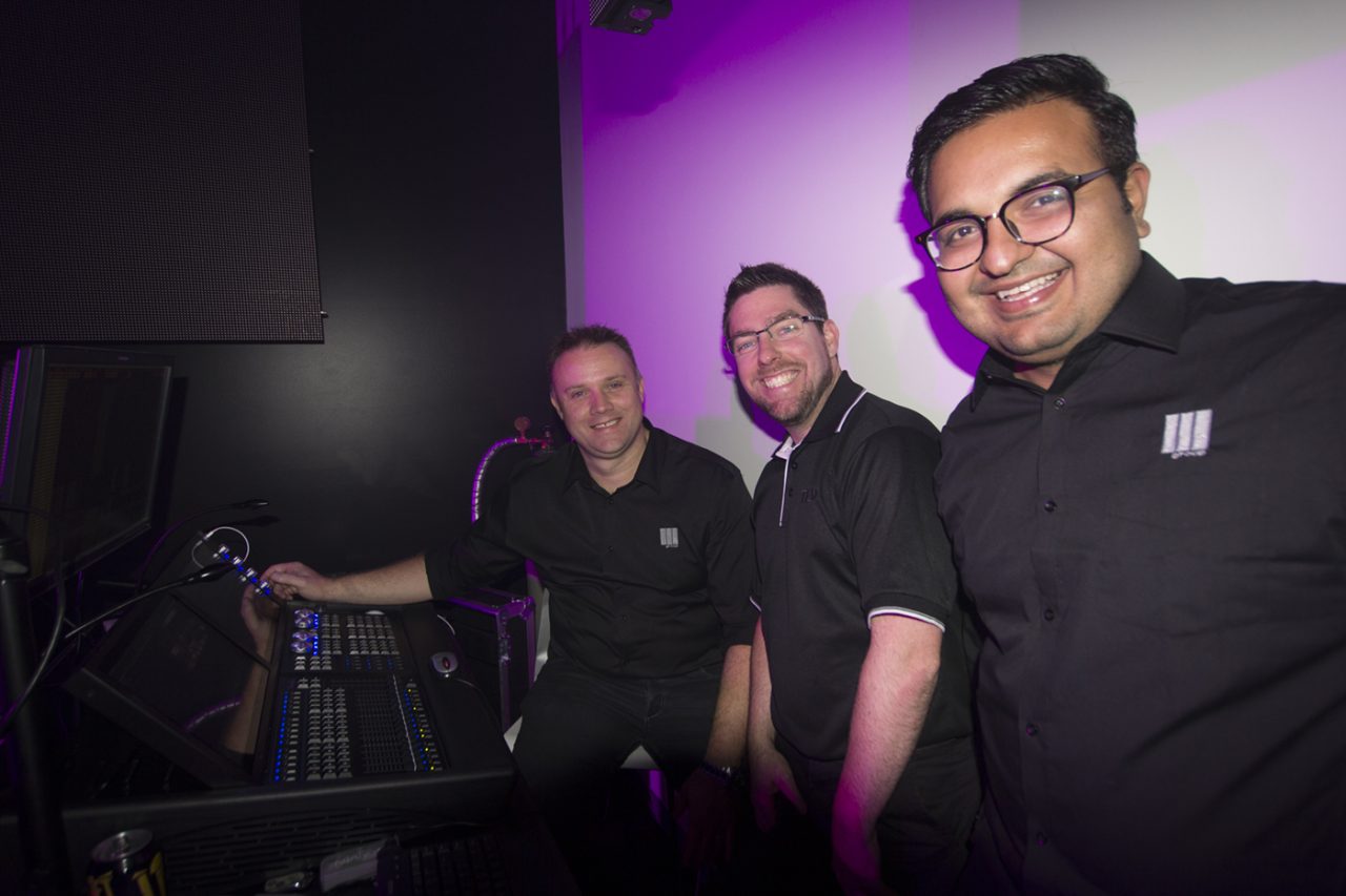 Three guests beside a lighting console in the Queensland showroom.