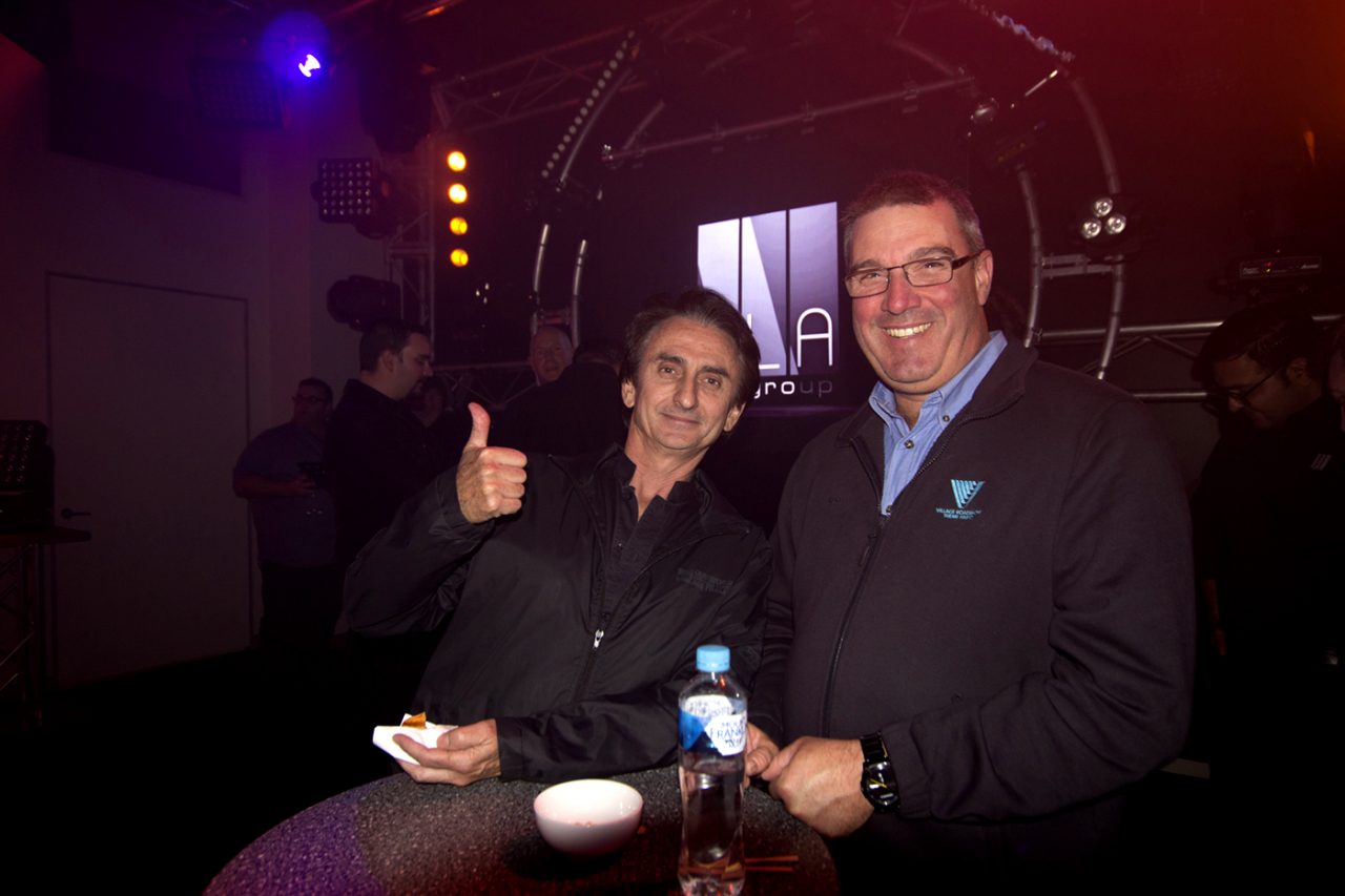 Two guests posing with refreshments at the Queensland showroom opening.