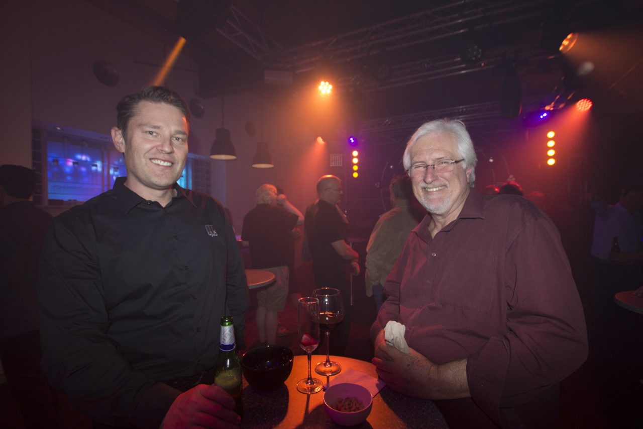 Two guests chatting beneath warm showroom lighting.