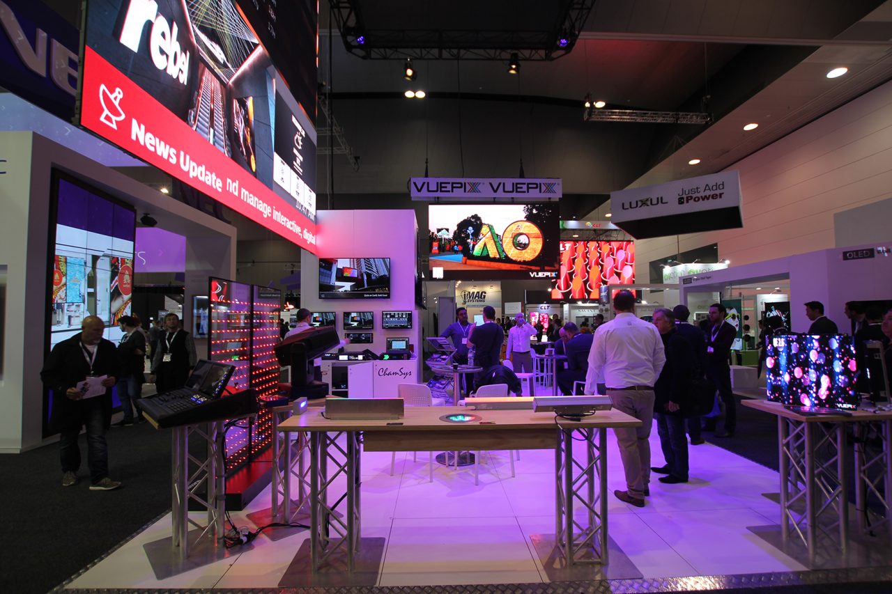 Visitors walking through the ULA stand with truss structures and bright screens.