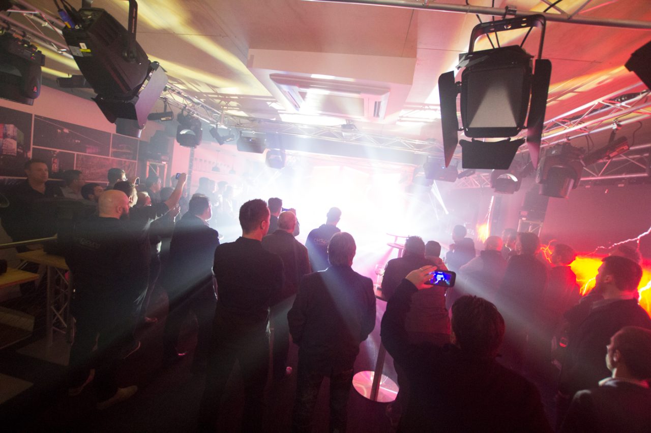 Guests silhouetted against red and white showroom lighting.