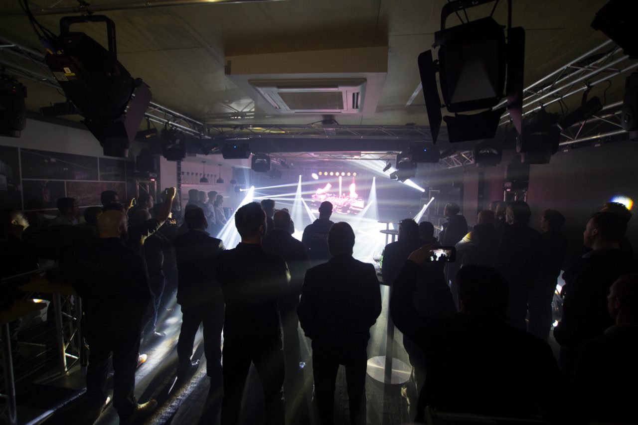 White beams extending through haze behind guests at the Melbourne showroom opening.