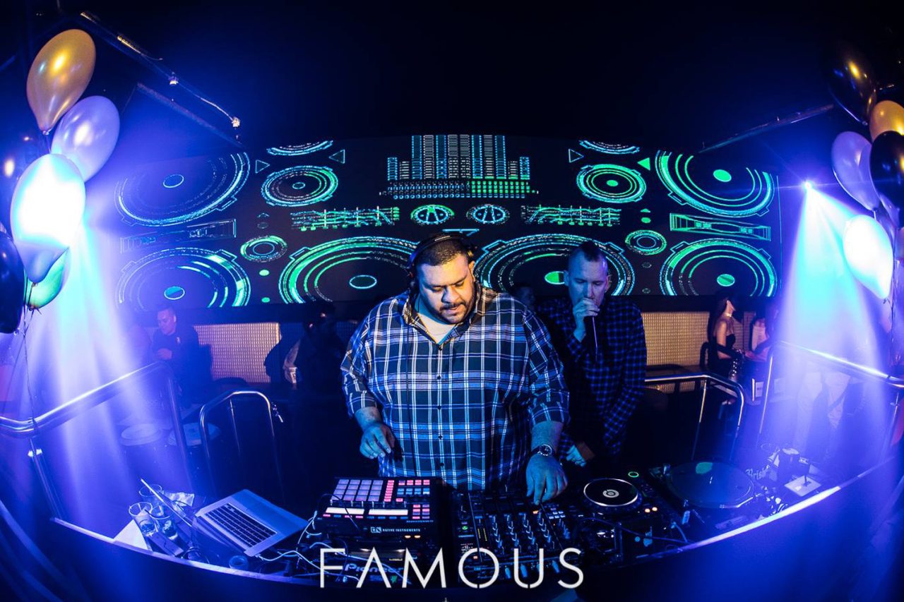 DJ at the mixing desk in front of green geometric screen graphics.