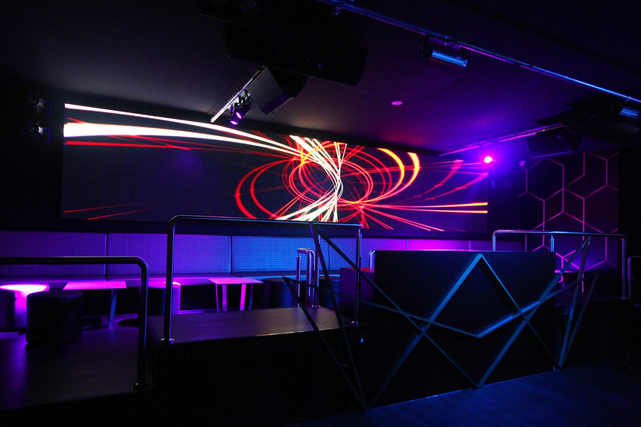Famous Brisbane DJ booth with red circular graphics on a panoramic LED screen.