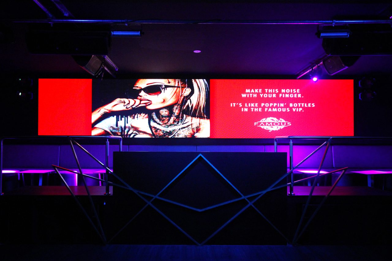 Red promotional graphics on the wide screen at Famous Night Club.