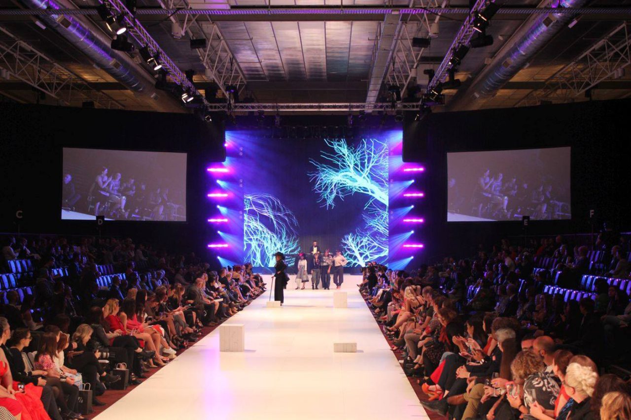 Full FashFest runway with seated spectators and a colourful central LED backdrop.