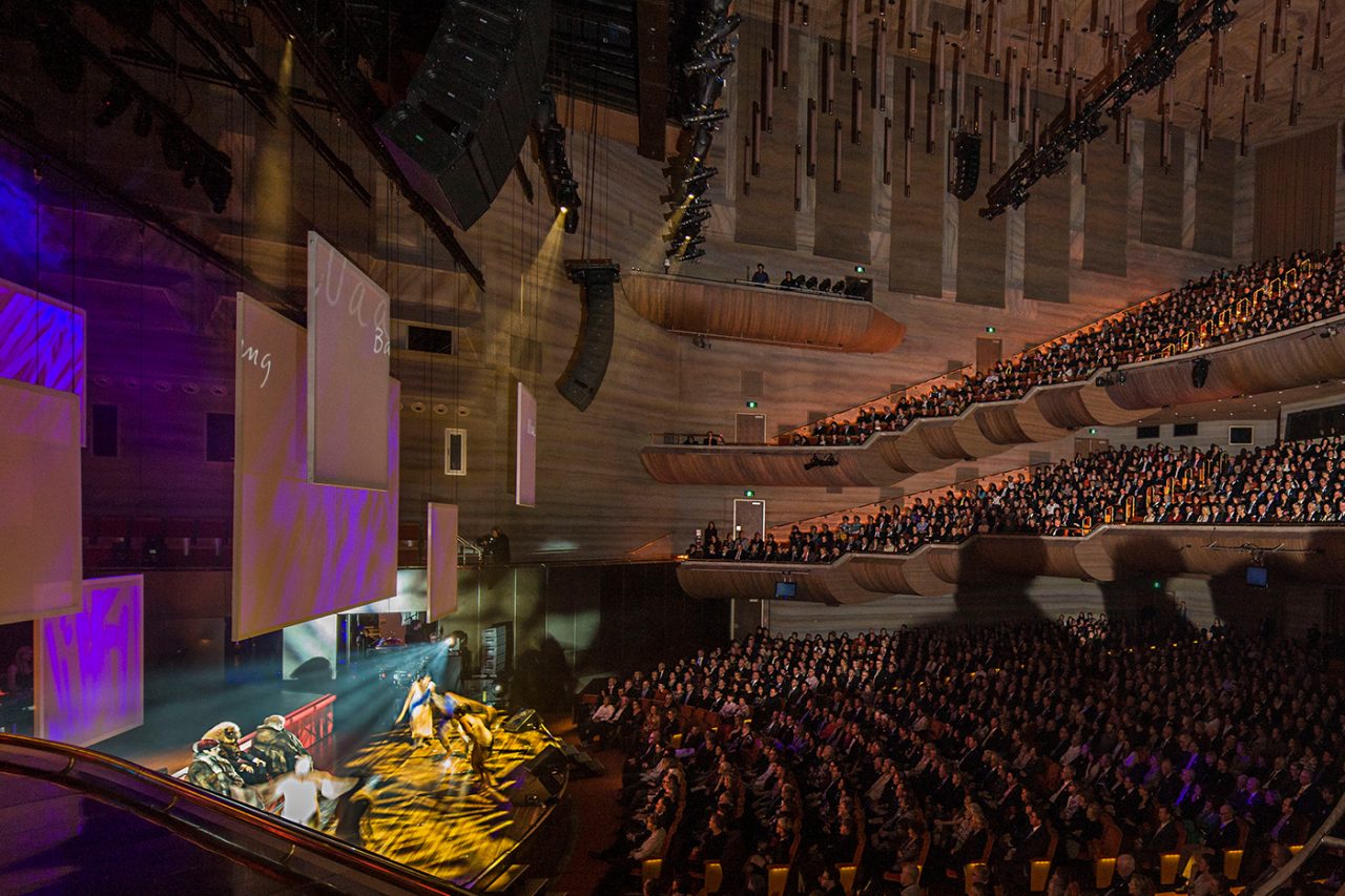 A performance in Hamer Hall beneath purple stage lighting at Arts Centre Melbourne.
