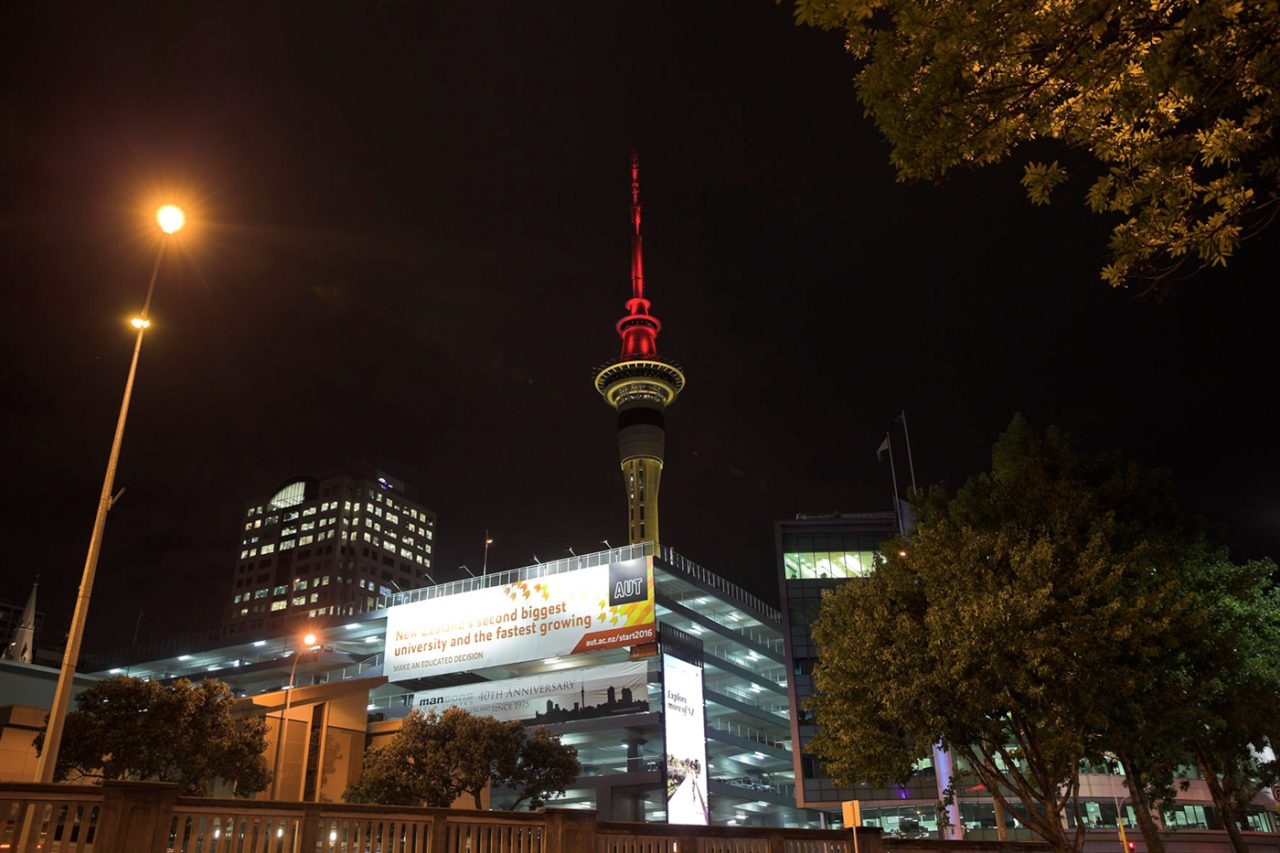 Street-level view of Auckland's Sky Tower with its red-lit spire.