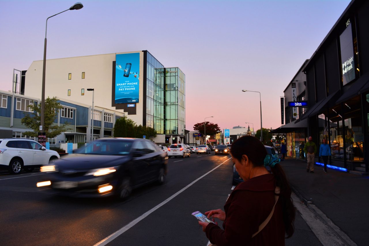 Blue advertisement on the vertical AURA Gateway billboard beside evening traffic.