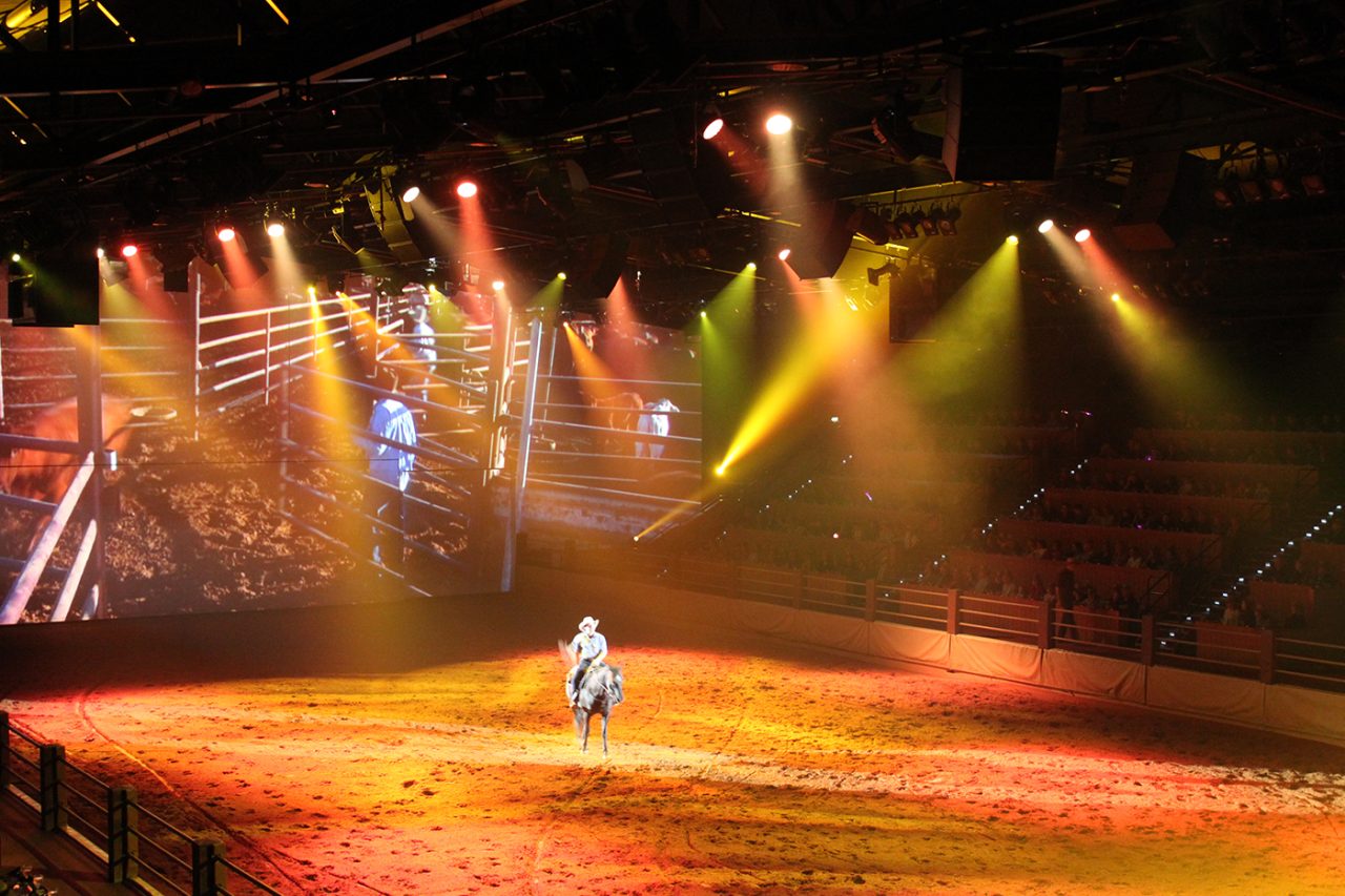 Amber lighting across a rider and the arena floor at Australian Outback Spectacular.