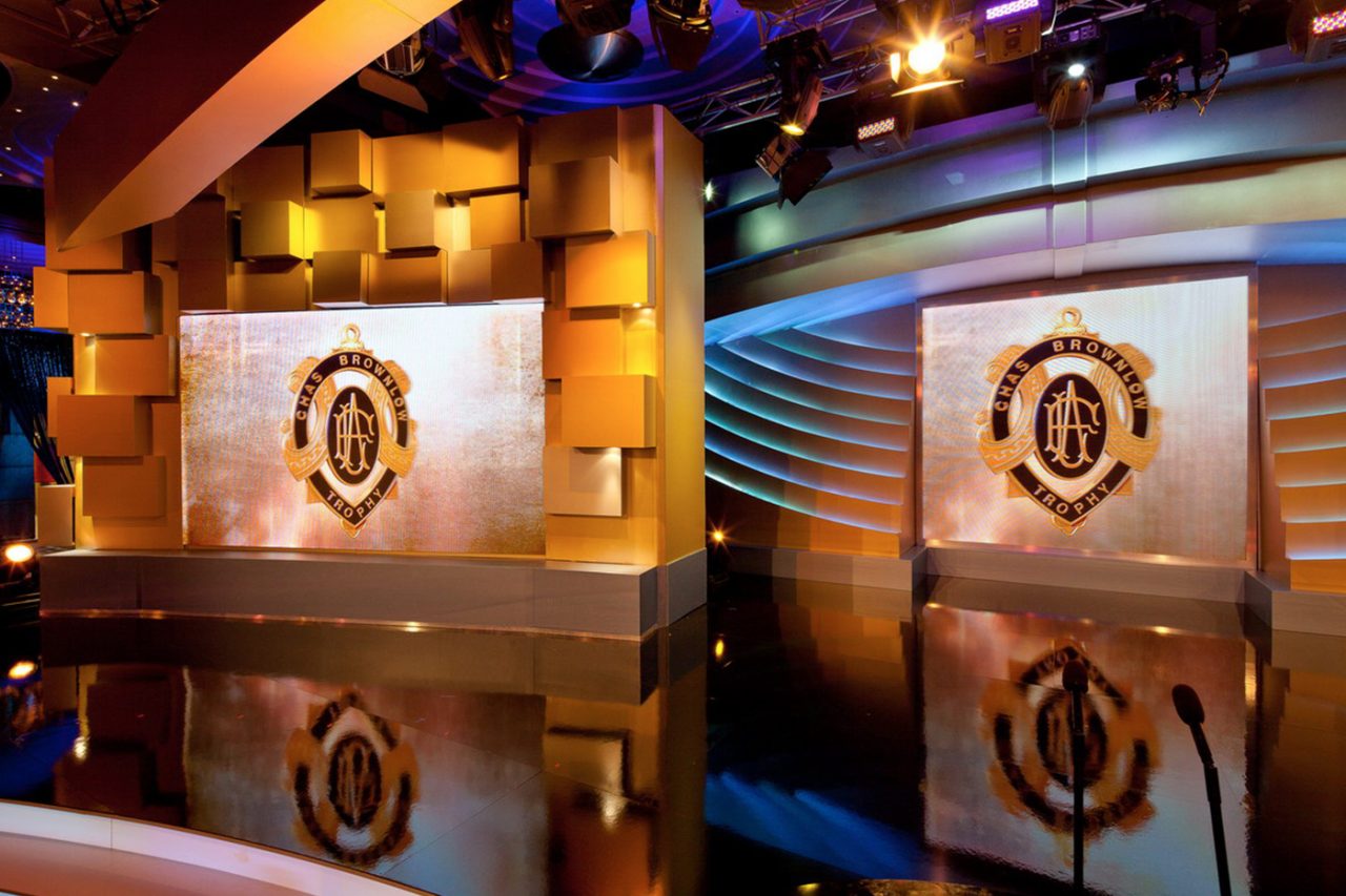 Brownlow Medal graphics reflected in the polished stage floor.