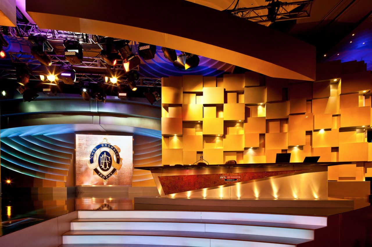 White steps leading to the Brownlow Medal stage beneath digital screens and gold panels.