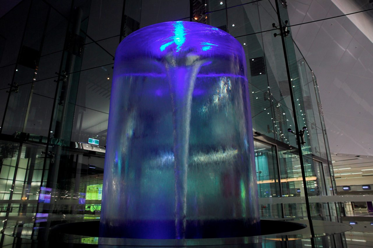 Close view of a cylindrical water feature illuminated in blue and purple.