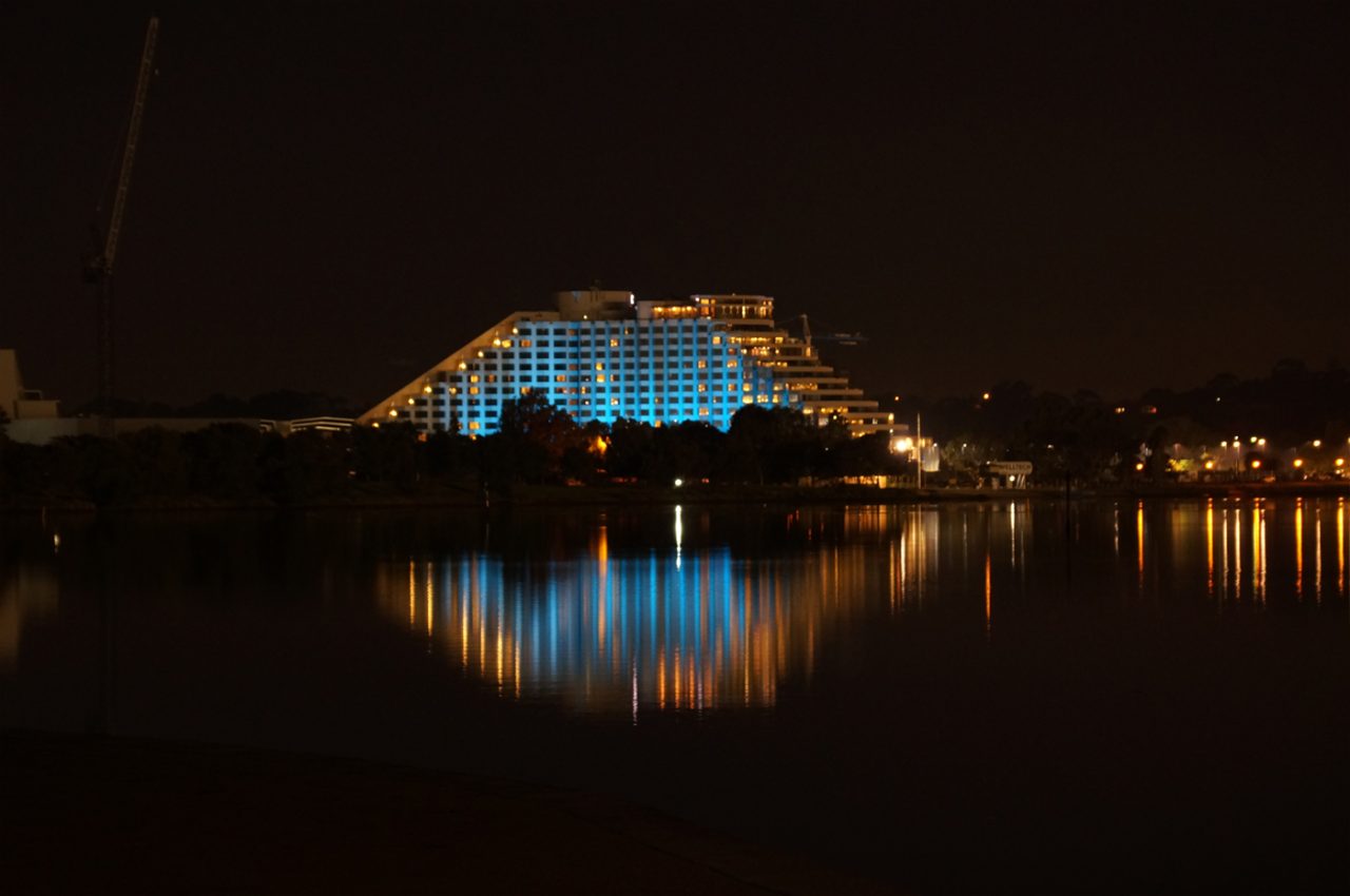 Blue lighting on Crown Perth reflected across the water at night.
