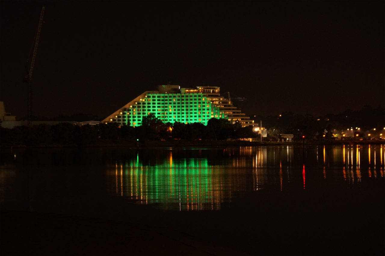 Green lighting across Crown Perth's facade reflected in the water.