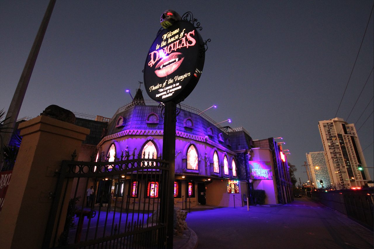 Dracula's sign beside the purple-lit restaurant facade at night.