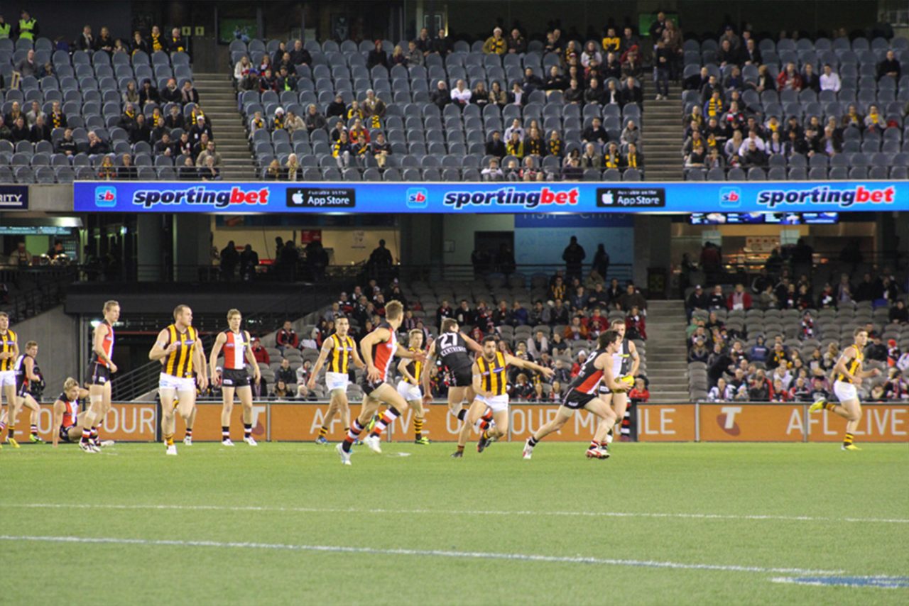 Blue digital advertising along the stands during a football match at Etihad Stadium.