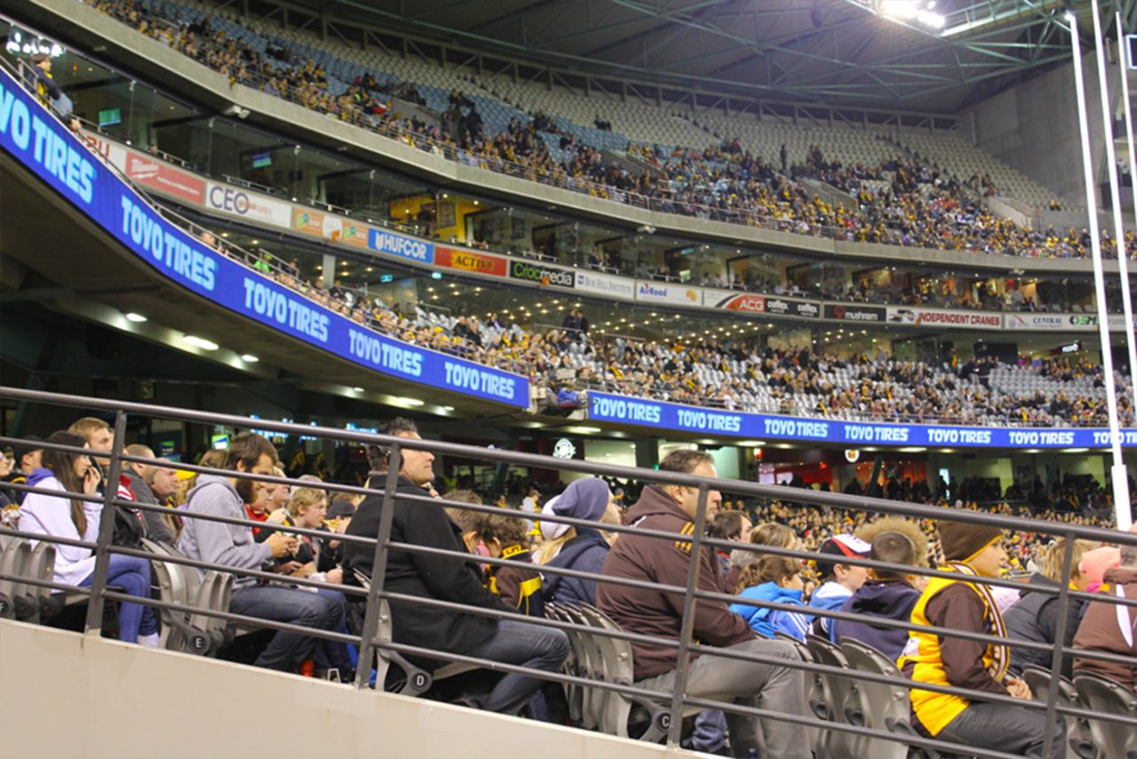 View across the stadium seating towards a blue digital advertising ribbon.