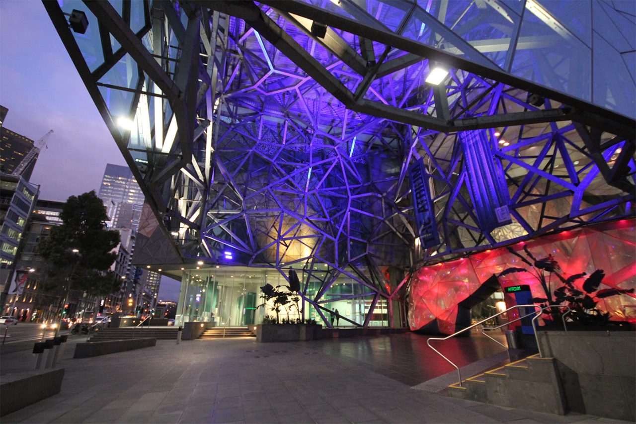 Purple illumination through Federation Square's atrium at dusk.