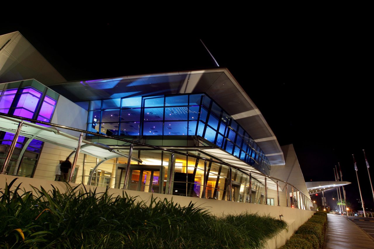 Blue and purple lighting across the glass facade at GCCEC at night.