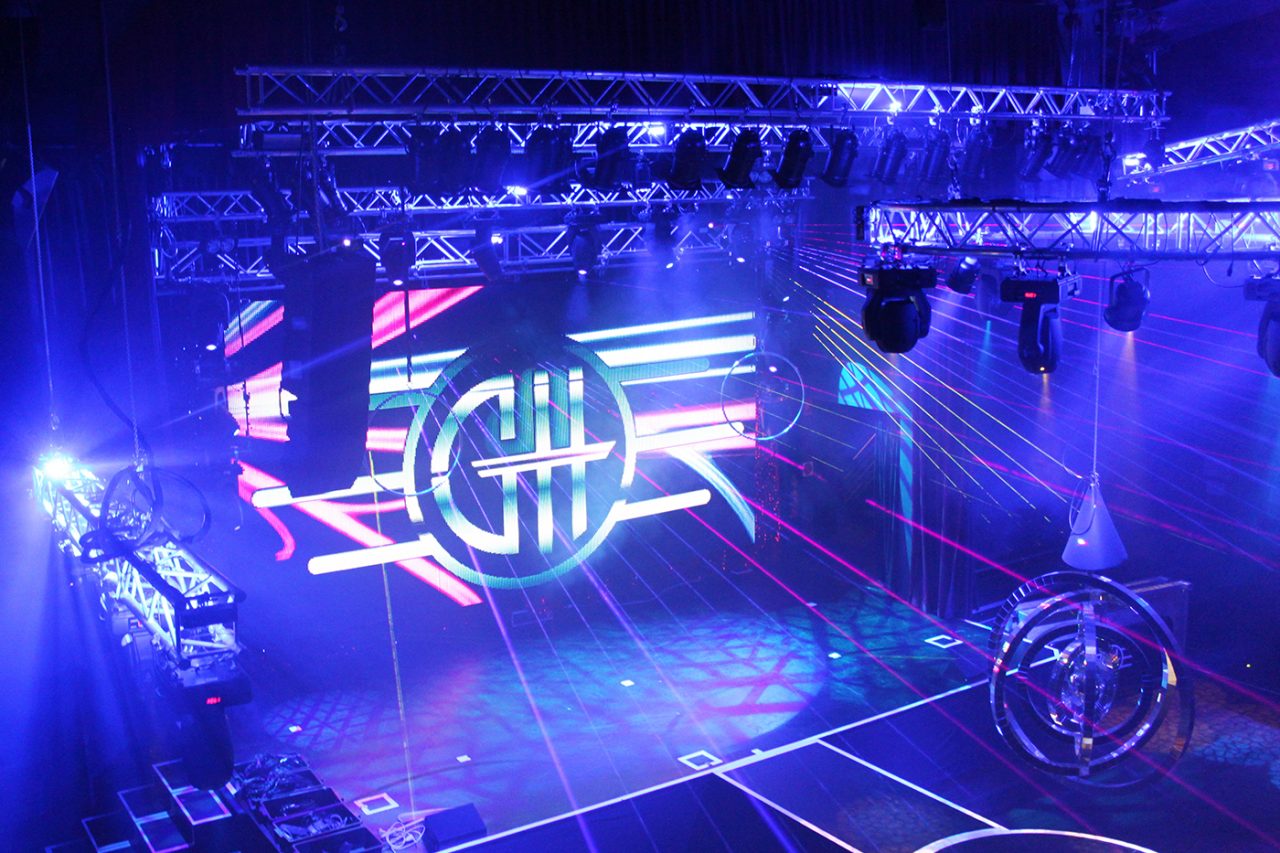 Blue lighting and laser beams around the GH Hotel stage screen.