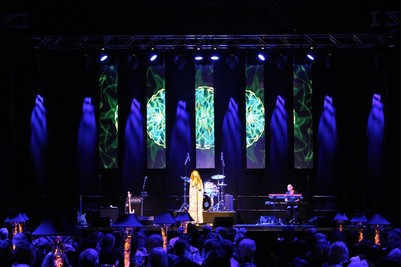 Wide view of the blue-lit stage and vertical screens at Gladstone Entertainment Centre.