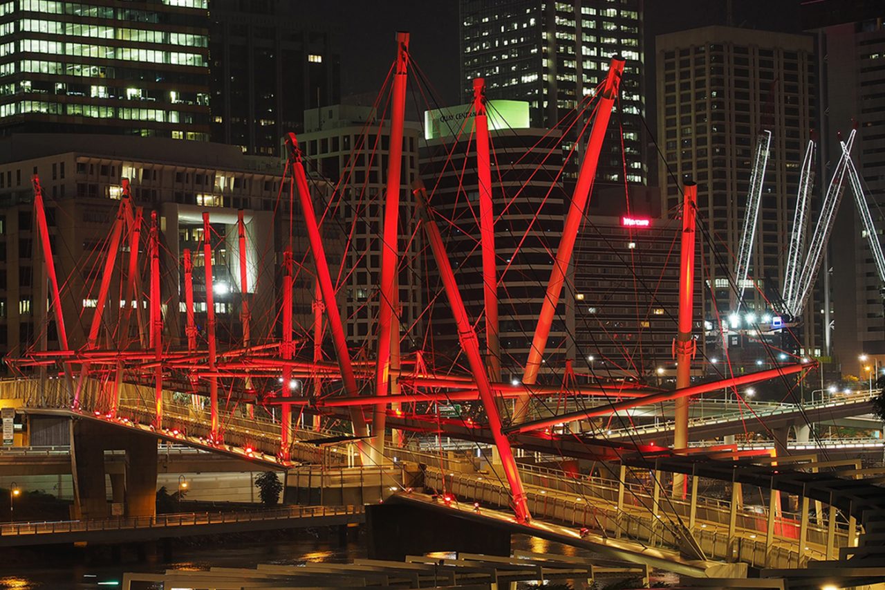 Red lighting on the angled masts of Brisbane's Kurilpa Bridge.