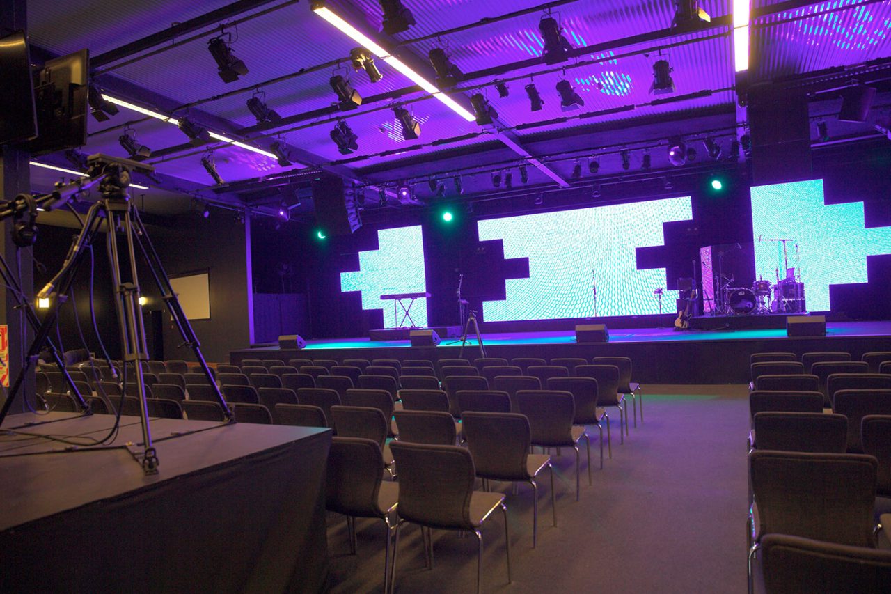 Empty seating faces a stage with geometric LED panels at Life Church in Auckland.