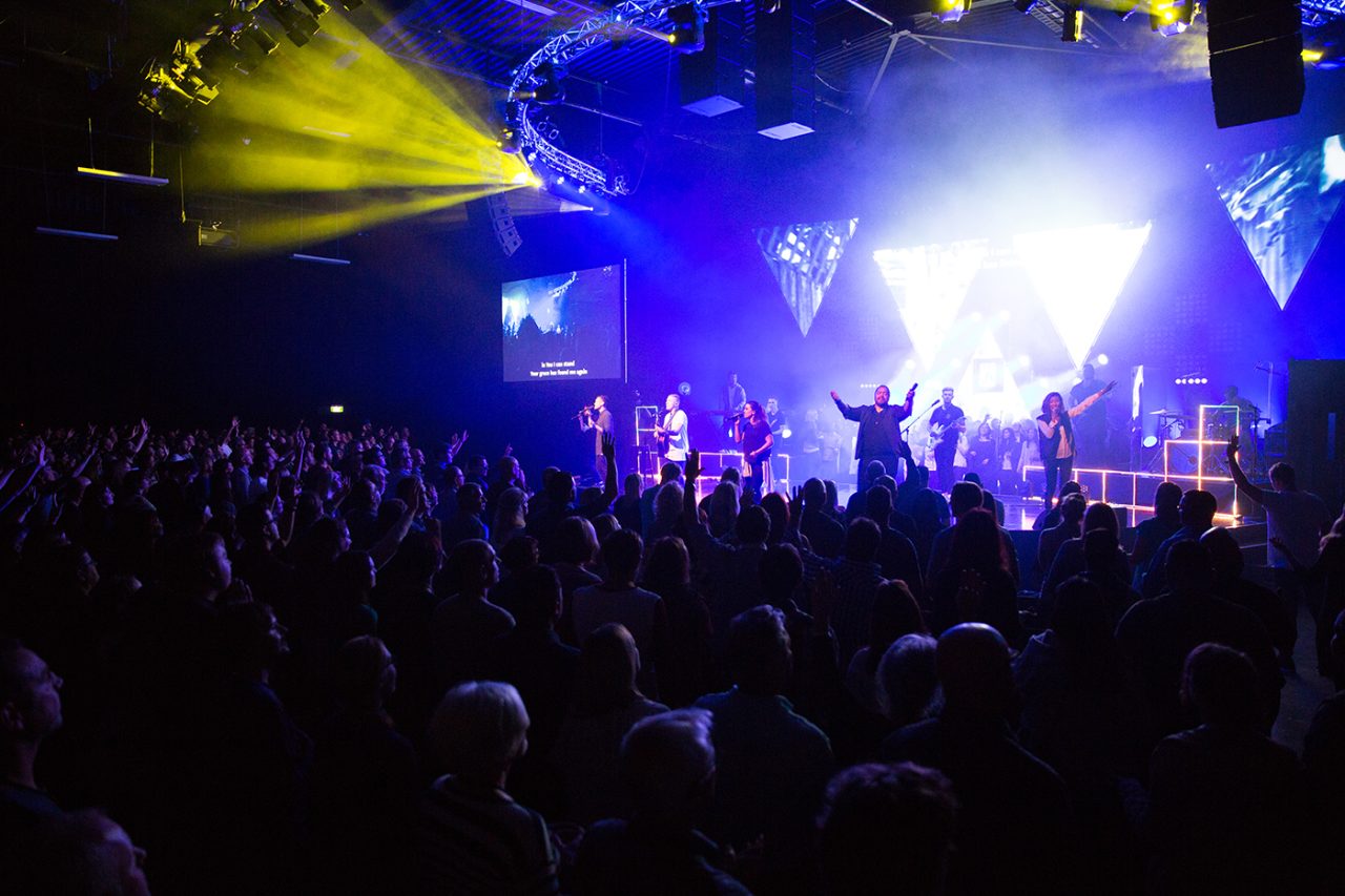Yellow and blue beams above the band and congregation at Life Church.