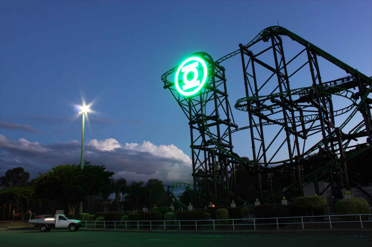 Illuminated Green Lantern emblem beside the rollercoaster at Movie World at dusk.