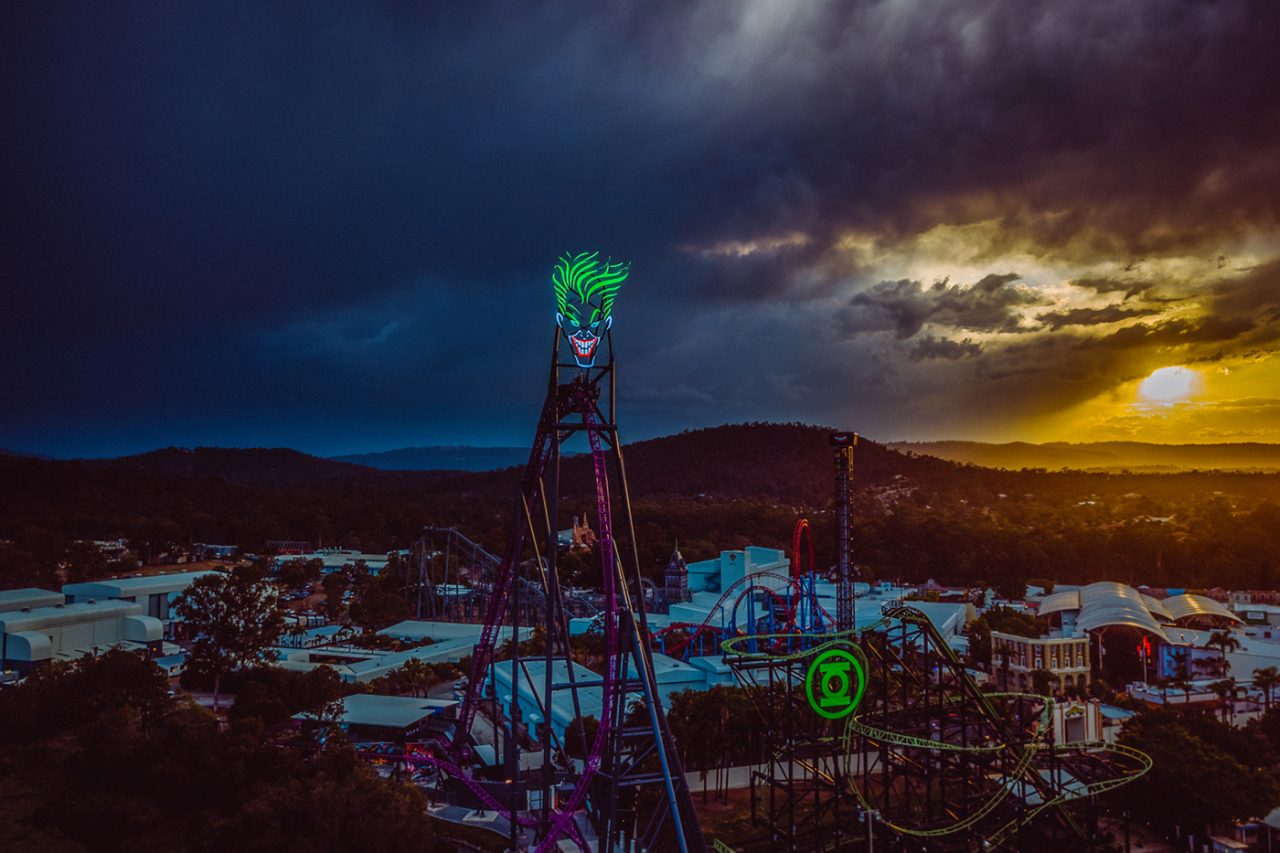 Joker and Green Lantern signs rise above Movie World's rides at dusk.