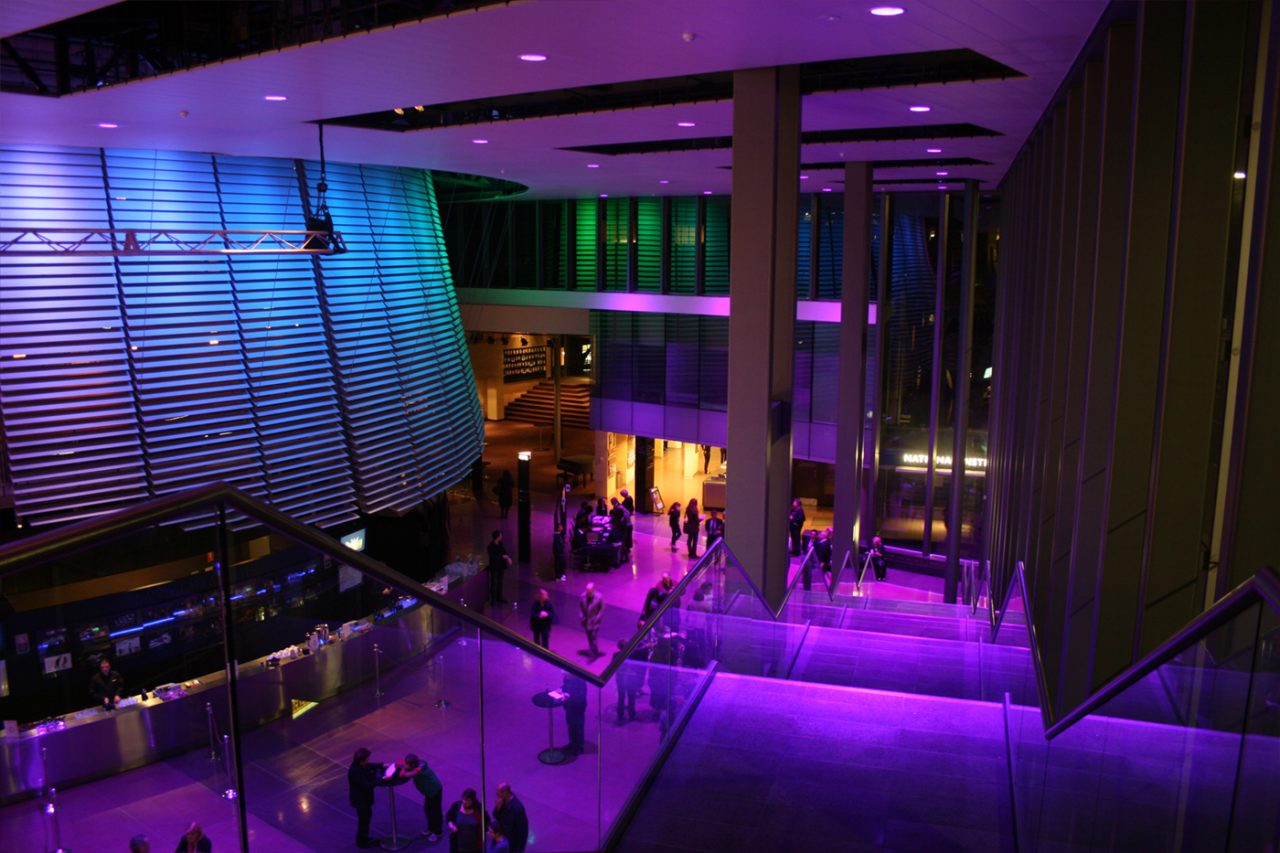 Purple and blue architectural lighting in the National Institute of Dramatic Art foyer.